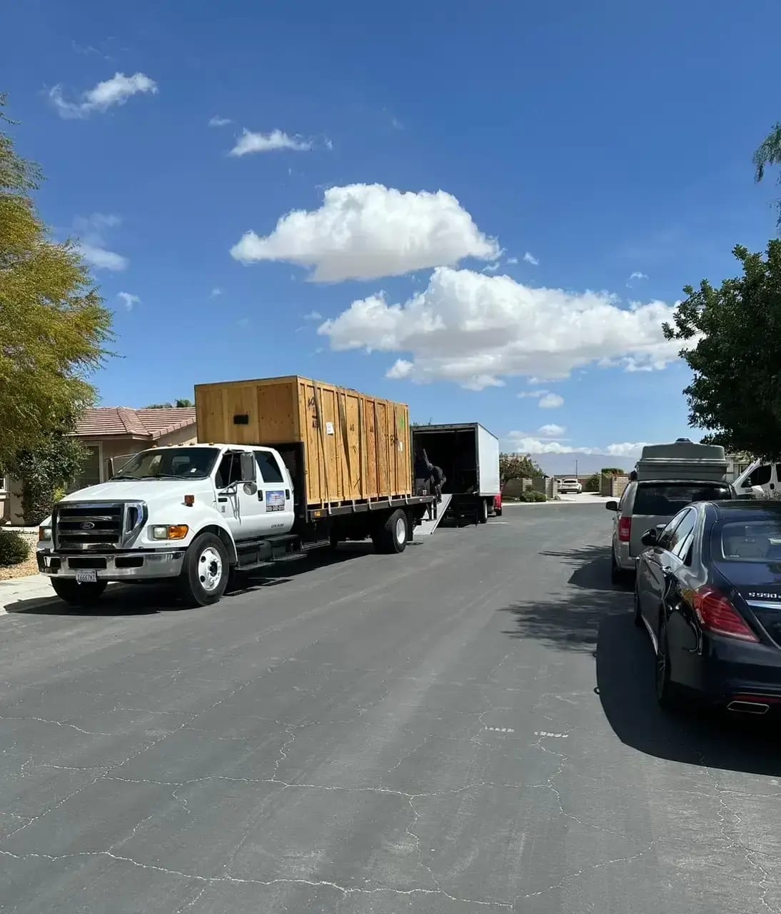 Flatbed moving truck carrying large wooden storage crates parked on a residential street.