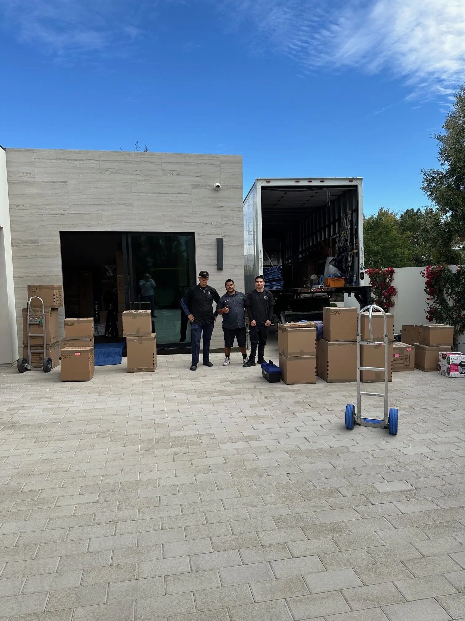 Professional residential moving crew posing outside a Palm Desert luxury home with loaded boxes and truck.