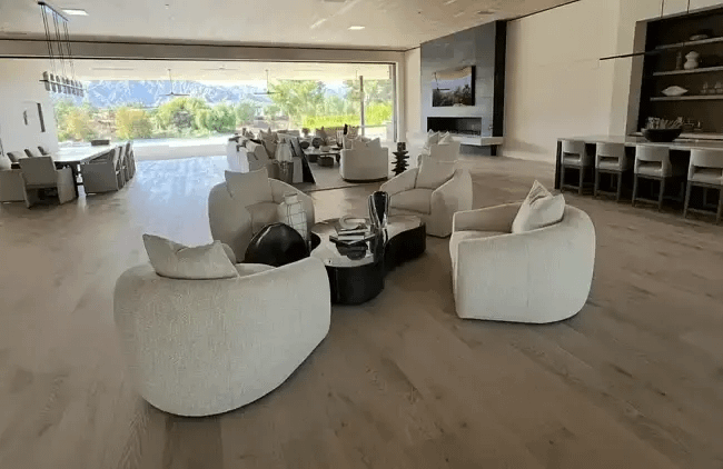 Spacious open-concept modern luxury living room styled with white curved armchairs and floor-to-ceiling glass doors in Palm Desert.
